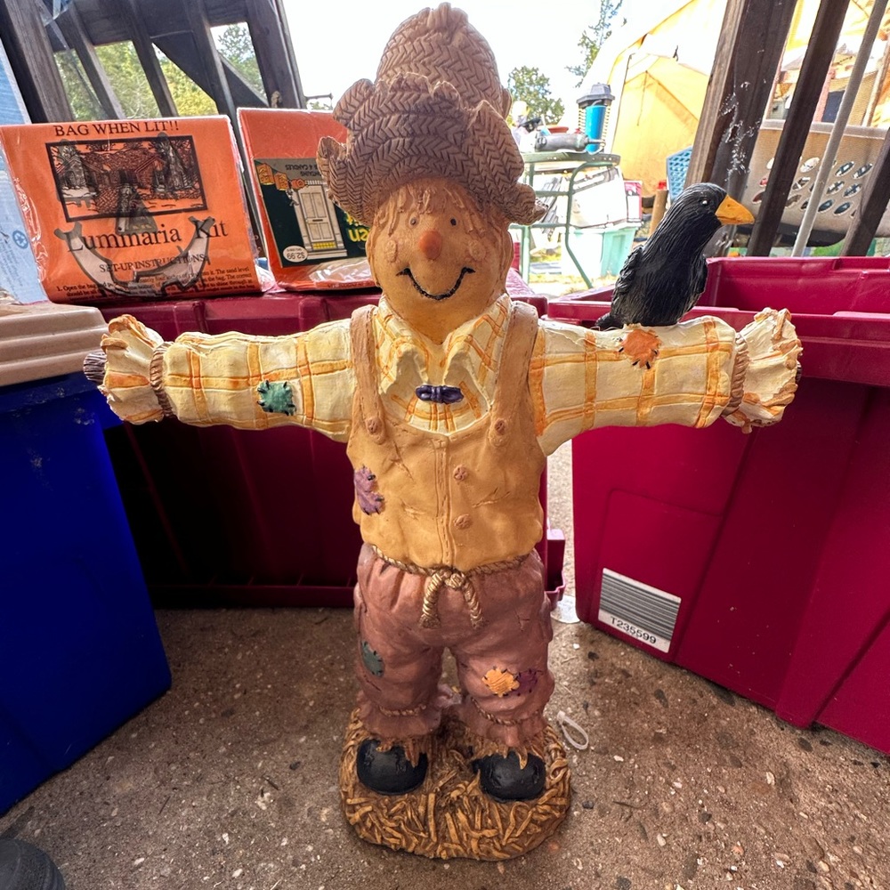 Scare crow statue with a crow on arm